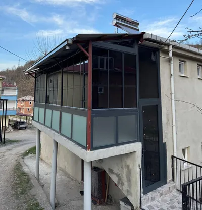 Antrasit profilli cam balkon, kolonlar üzerindeki teras katını baştan başa kapatıyor, alt sıraları buzlu cam